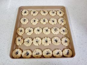 把小剂子放手心揉圆，用掌心压扁一点，放不粘烤盘，再用大拇指在中间压一下，撒黑芝麻【也可以撒一层鸡蛋液再撒黑芝麻】