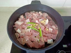浸泡好的牛肉冷水下锅，加入葱段，生姜片。