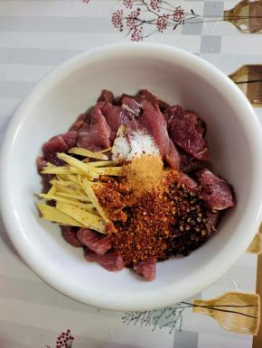 碗中放入姜丝，一大勺料酒，一勺盐，两勺五香粉，三勺辣椒粉，一小把花椒！（喜欢吃辣的就多放一些辣椒粉！不喜欢吃辣的也可以不放辣椒粉，做成五香口味的也很好吃！）