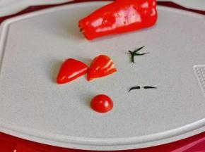 红甜椒只用尖部做帽子，小番茄只有顶部做鼻子，小番茄蒂上叶子做眉毛。（用海苔做眉毛也可以）