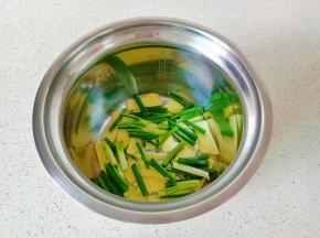 压力锅内胆铺上一层姜片与葱段。