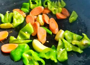 起锅热油，爆香大蒜，加入青椒火腿炒香，