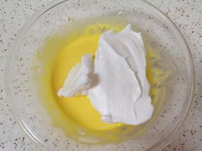 打发好的蛋白取三分之一加入到蛋黄糊里面，用硅胶刮刀采用切拌和翻拌的手法混合均匀。 