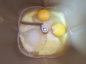 先将玉米油和牛奶加入面包桶中，磕入鸡蛋，加入细砂糖。 