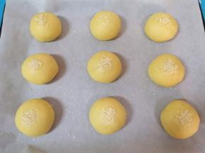 烤盘里铺油纸，放上做好的喜饼生胚，表面刷上一层水，撒上熟白芝麻。