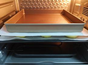 发酵好的喜饼明显变大，上面盖上一层油纸，放上一个烤盘。 