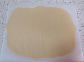 台面上铺一张油纸，取一块冷藏过的面团放在油纸上，再盖上一层油纸擀开。 