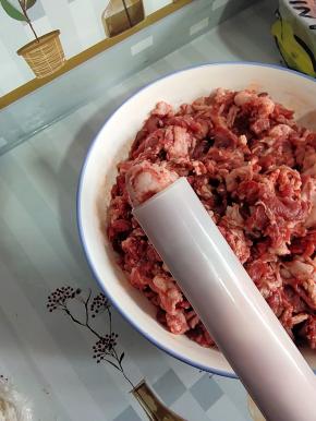 轻轻转动灌肠器，把肉挤出来一点儿！（这样套猪肠衣的时候，就不会把肠衣刮破！）