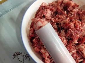 轻轻转动灌肠器，把肉挤出来一点儿！（这样套猪肠衣的时候，就不会把肠衣刮破！）