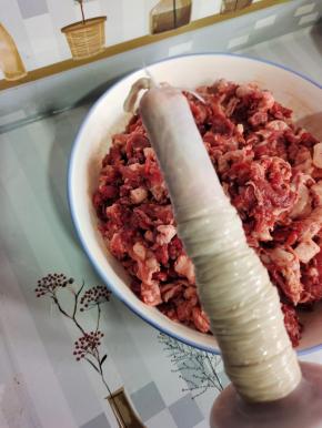 把猪肠衣挤干水分，套在灌肠器上！再在顶端打一个结！（或者用棉绳扎紧也可以！）