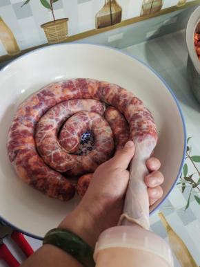 一只手轻轻捏住肠衣，另一只手转动灌肠器，就可以把肉均匀的灌进猪肠衣里！