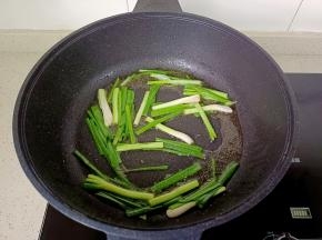 锅里留一点底油，下葱段炒出香味。