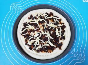 在饼底抹上香辣肉酱，撒上少许马苏里拉芝士。 