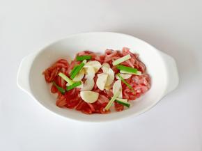 把里脊肉放在容器里，加上蒜片葱段。