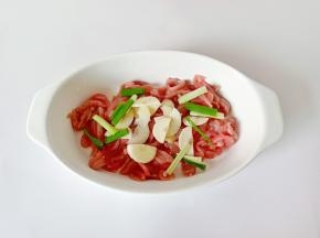 把里脊肉放在容器里，加上蒜片葱段。