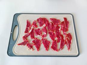 牛肉撕去筋膜，清洗后顺着纹路横切片。