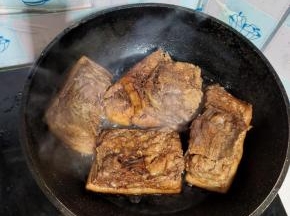 锅里倒入适量的油，油热后转小火，然后把抹上酱油的肉放入油锅里面煎！猪皮朝下放！