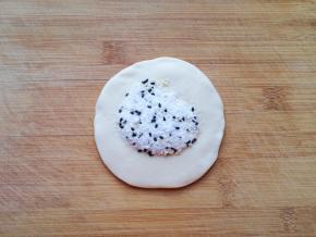 取一份面团压扁擀开，放上糖馅。 