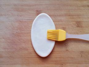 擀成牛舌状，饼胚表面刷上一层水。 