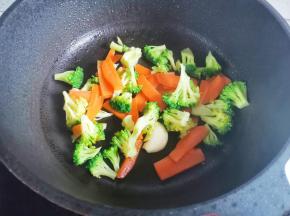 另起锅热油，放入大蒜爆香，加入西兰花、胡萝卜炒出水分，