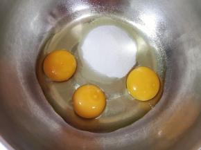 打蛋盆里磕入3个鸡蛋，加入细砂糖。 