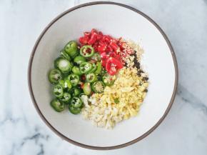 调酱汁：碗中放青红辣椒、熟芝麻、葱、蒜末，