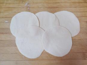 将小剂子压扁，擀成椭圆形的菜盒皮。