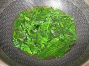 锅内倒入少许纯净水烧开，放入食用碱和菠菜叶，用筷子搅拌均匀。