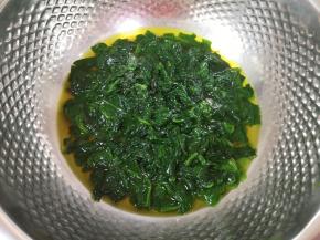 将煮好的菠菜叶带汤汁一起倒进盆里晾至温热（菠菜叶带汤汁一共是208g）。 