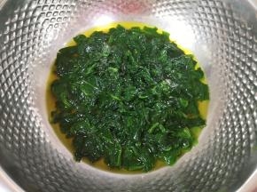 将煮好的菠菜叶带汤汁一起倒进盆里晾至温热（菠菜叶带汤汁一共是208g）。 