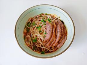 把煮好的米粉放在汤碗里，加上切好的牛肉片。