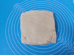 将拌好的面絮倒在揉面垫上，用刮板翻拌按压成无干粉的面团。