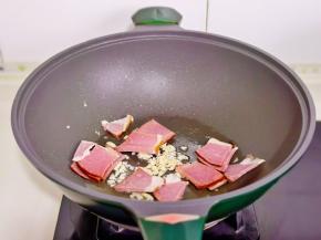 起油锅加入蒜末辣椒炒香，再加入腊肉翻炒。