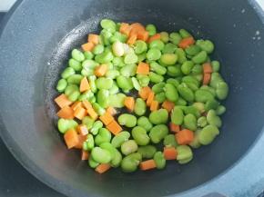 锅中热油，放入蚕豆米胡萝卜翻炒一分钟，