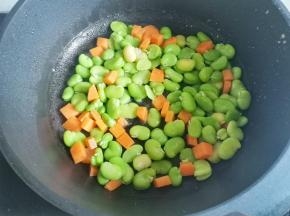 锅中热油，放入蚕豆米胡萝卜翻炒一分钟，