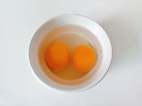 碗里磕入两个鸡蛋。