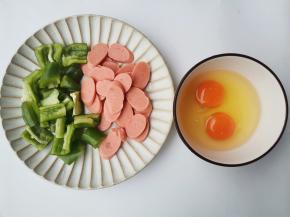 青椒切块，火腿切片，鸡蛋打入碗中打散备用。