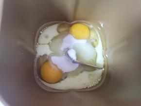 先将玉米油和牛奶加入面包桶中，磕入鸡蛋，加入细砂糖。 