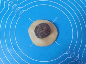 取一份松弛好的面团，擀开放上豆沙馅，和包蛋黄酥的手法一样，用虎口慢慢向上推挤收口。 