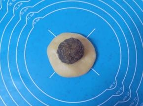 取一份松弛好的面团，擀开放上豆沙馅，和包蛋黄酥的手法一样，用虎口慢慢向上推挤收口。 