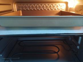  发酵好的喜饼明显变大，上面盖上一层油纸，放上一个烤盘。
