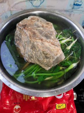 一双筷子交叉放在萝卜缨上，再在上面压上一个大石头！（让萝卜缨全部浸泡在水里面！）