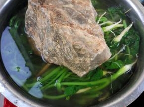 一双筷子交叉放在萝卜缨上，再在上面压上一个大石头！（让萝卜缨全部浸泡在水里面！）