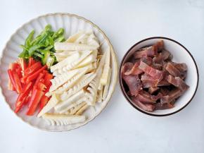 准备食材，野竹笋去掉外皮提前用开水烫一下浸泡一天。再将春笋、腊肉切条，青红椒切丝。