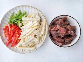 准备食材，野竹笋去掉外皮提前用开水烫一下浸泡一天。再将春笋、腊肉切条，青红椒切丝。