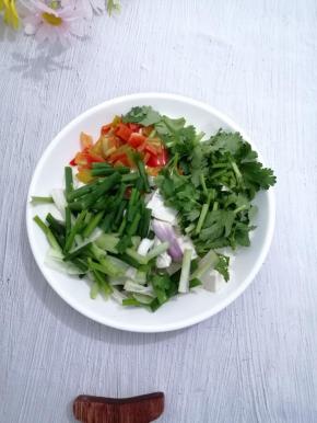 把焯好水的豆腐放入盘子中，加入香菜、小葱和青椒