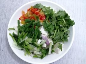 把焯好水的豆腐放入盘子中，加入香菜、小葱和青椒