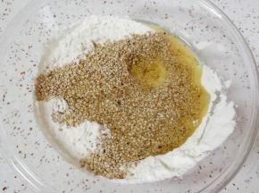 混合好的低筋面粉里面加入玉米油和白芝麻，用筷子搅拌均匀。
