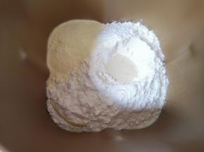 加入奶粉和高筋面粉，面粉中间挖个小洞放入干酵母，用面粉盖起来。 