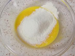 搅打至蛋黄、牛奶和玉米油完全融合，筛入60g低筋面粉。 